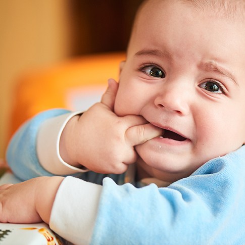 Baby chewing on fingers while teething