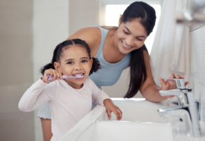 a parent showing their child how to brush their teeth