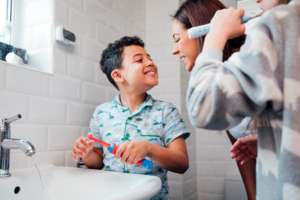 a parent helping her child brush his teeth 